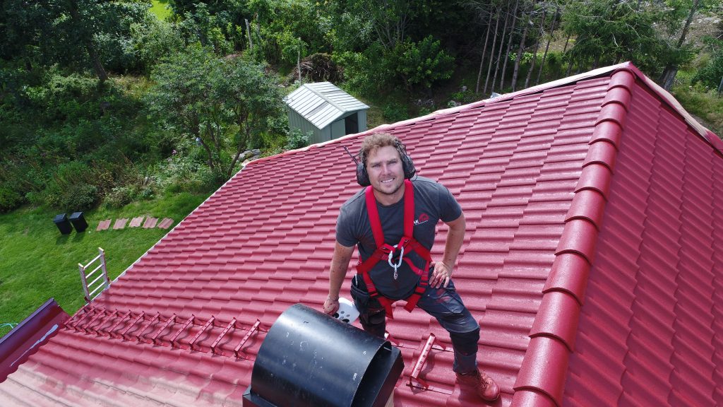 Medarbetare som står uppe på ett nymålat rött hustak